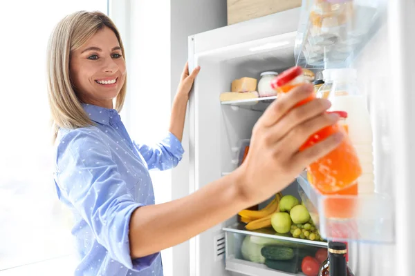 Nő vesz üveg a lé ki a hűtőszekrény a konyha — Stock Fotó
