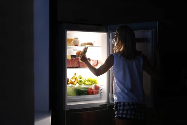 Žena si v noci bere sendvič z ledničky v kuchyni — Stock fotografie