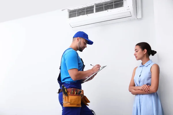 Técnico profissional falando com a mulher sobre ar condicionado dentro de casa — Fotografia de Stock