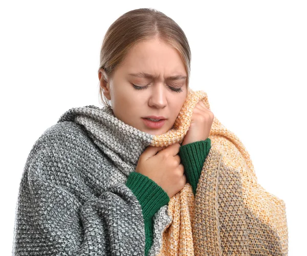 Молода жінка, загорнута в теплу ковдру, страждає від холоду на білому тлі — стокове фото