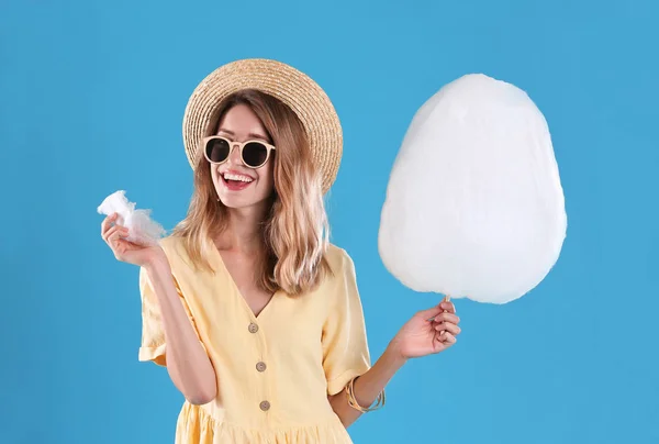 青い背景に綿菓子を食べる幸せな若い女性 — ストック写真