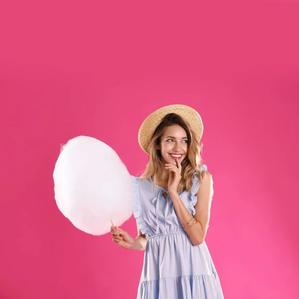 Gelukkige jonge vrouw met suikerspin op roze achtergrond — Stockfoto