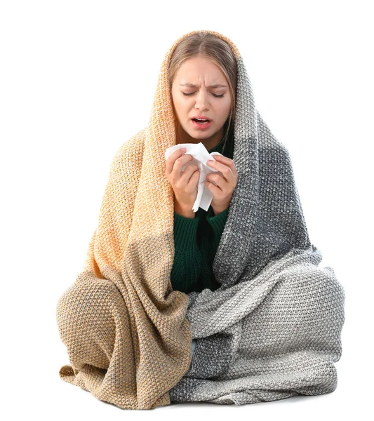 Mujer joven envuelta en manta caliente que sufre de frío sobre fondo blanco — Foto de Stock