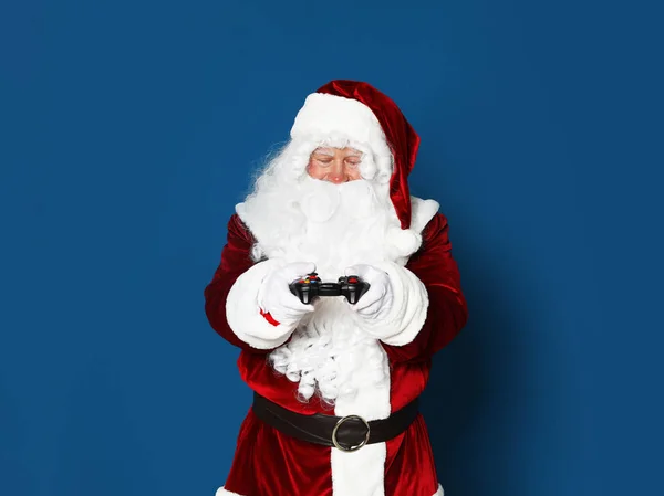 Autêntico Papai Noel com controlador de jogo em fundo azul. Espaço para texto — Fotografia de Stock