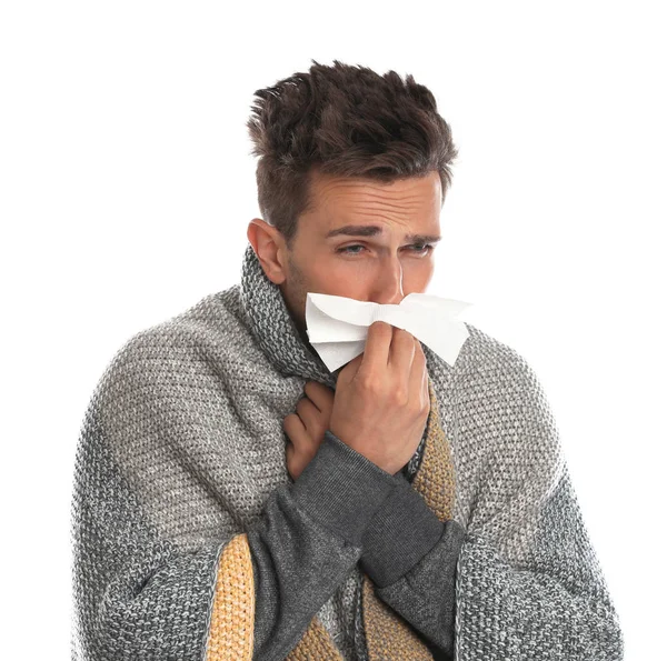 Jeune homme enveloppé dans une couverture chaude souffrant de froid sur fond blanc — Photo