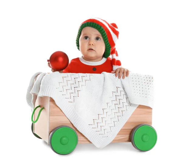 Bebê bonito usando chapéu de elfo em carrinho de madeira no fundo branco. Primeiro Natal — Fotografia de Stock