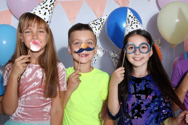 Niños felices con accesorios de cabina de fotos en la fiesta de cumpleaños en el interior —  Fotos de Stock