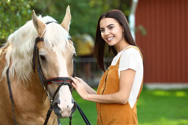 Palomino horse in bridle and young woman outdoors — Stock Photo, Image