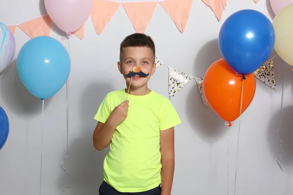 Menino feliz perto de balões brilhantes na festa de aniversário dentro de casa — Fotografia de Stock