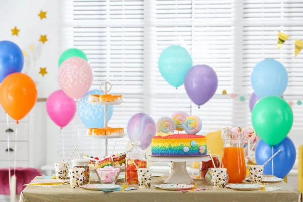 Gâteau d'anniversaire lumineux et autres friandises sur la table dans la chambre décorée — Photo