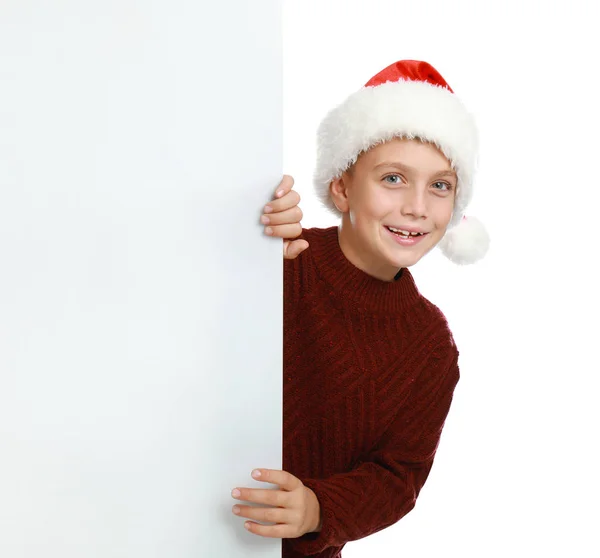 Criança feliz em chapéu de Papai Noel espreitando fora do banner em branco no fundo branco. Celebração de Natal — Fotografia de Stock