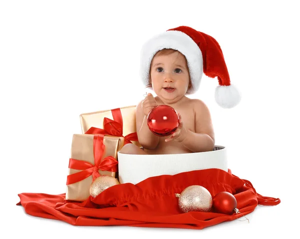 Симпатичный маленький ребенок в шляпе Санты с рождественскими подарками сидя в коробке на белом фоне — стоковое фото