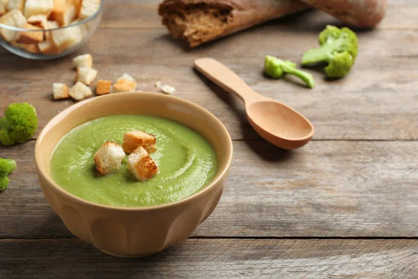 Bol de soupe à la crème de brocoli avec croûtons servi sur une table en bois, espace pour le texte — Photo