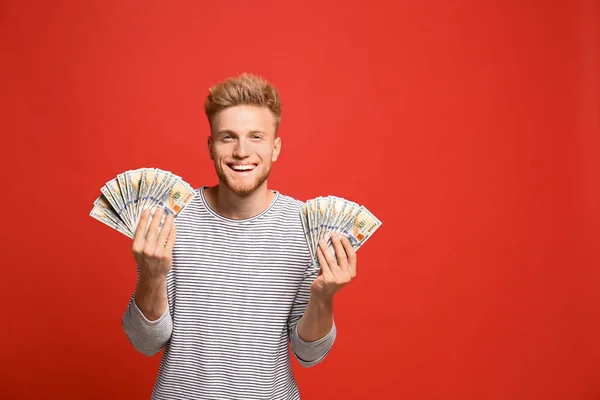 Portrait of happy lottery winner with money on red background — Stock Photo, Image