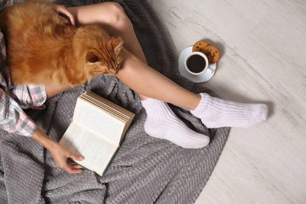 Nő aranyos piros macska és könyv a padlón, felülnézet — Stock Fotó