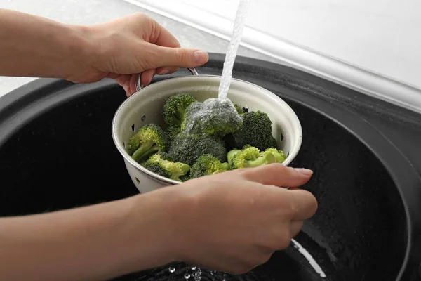Wanita mencuci brokoli hijau segar dalam colander logam di bawah air keran, closeup — Stok Foto