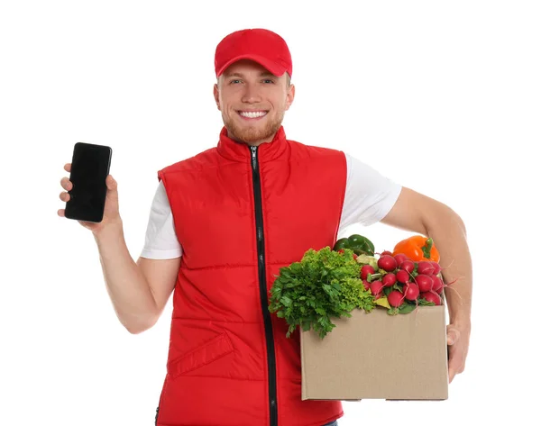 Entrega homem com caixa de legumes frescos e smartphone no fundo branco, mockup para design — Fotografia de Stock