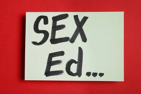 Trozo de papel con texto "SEXO ED"... sobre fondo rojo, vista superior — Foto de Stock