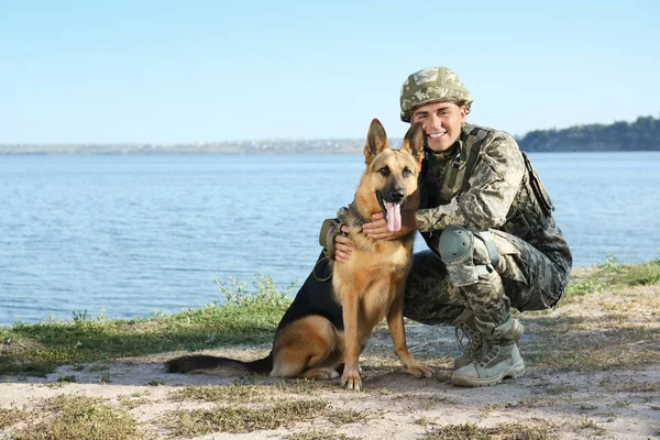 Mann in Militäruniform mit Schäferhund in Flussnähe, Platz für Text — Stockfoto