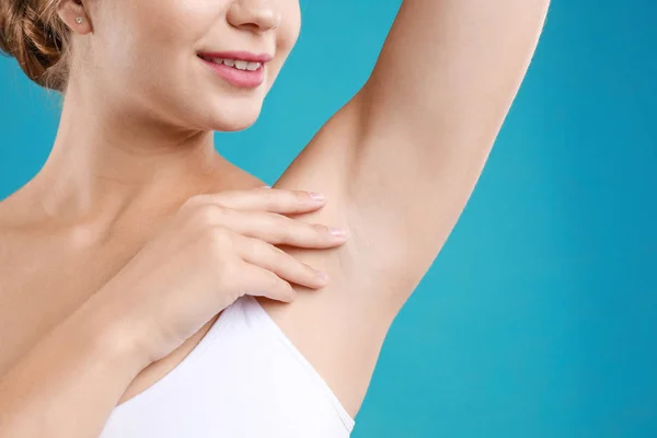 Ung kvinna med slät ren armhåla på Teal bakgrund, närbild. Använda deodorant — Stockfoto