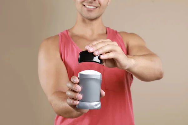 Joven sosteniendo desodorante sobre fondo beige, primer plano. Burla para el diseño —  Fotos de Stock