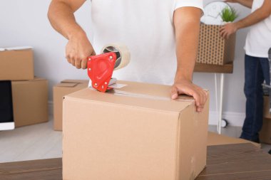 Ofiste karton kutu paketleyen genç işçi, yakın plan. Taşıma servisi