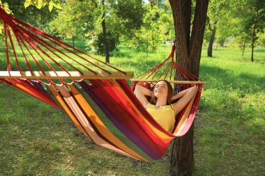 Genç bayan yeşil bahçedeki hamakta dinleniyor.