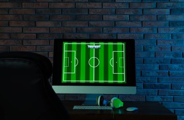 Modern bilgisayar ve kulaklıklar karanlık odada masada. Video oyunları oynanıyor