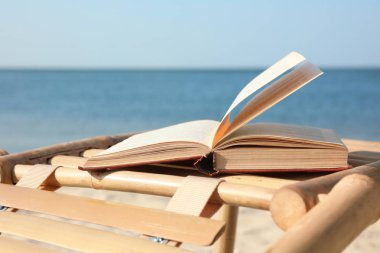 Deniz kenarında ahşap şezlong üzerinde kitap. Tatil sırasında okuma