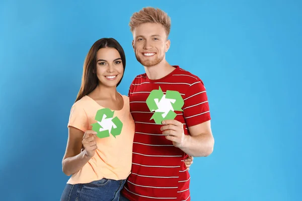 Pareja joven con símbolos de reciclaje sobre fondo azul —  Fotos de Stock