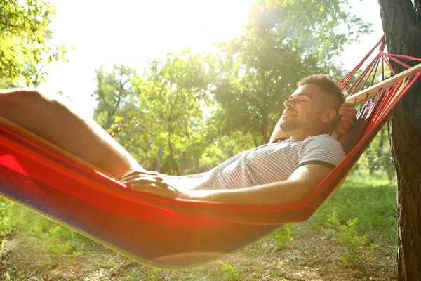 Jovem descansando em confortável rede no jardim verde — Fotografia de Stock