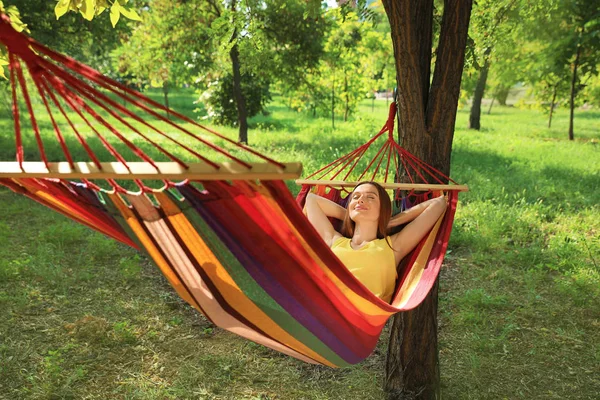 Mujer joven descansando en la hamaca cómoda en el jardín verde —  Fotos de Stock