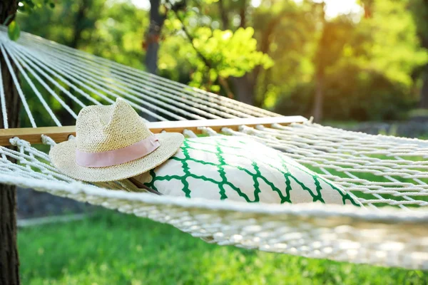 Bequeme Netzhängematte mit Kopfkissen und Hut im grünen Garten — Stockfoto