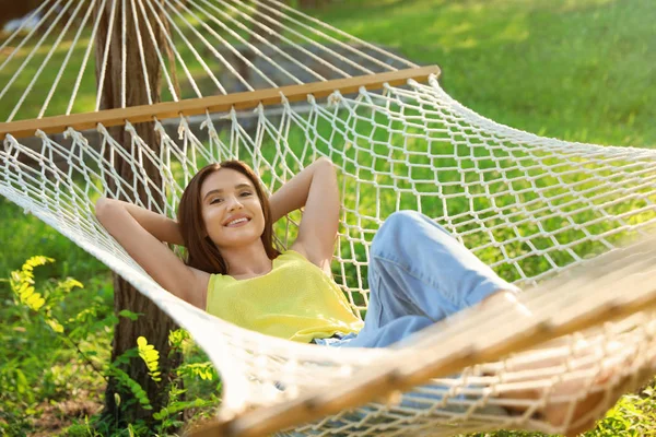 Młoda kobieta odpoczywa w komfortowym hamaku w zielonym ogrodzie — Zdjęcie stockowe