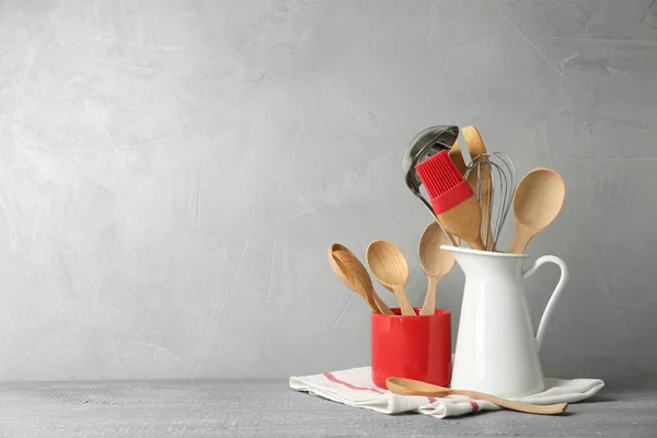 Utensílios de cozinha diferentes na mesa de madeira contra fundo cinza claro. Espaço para texto — Fotografia de Stock