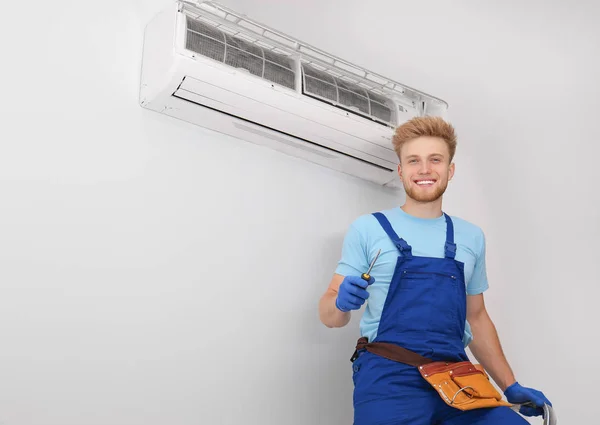 Técnico profissional perto de ar condicionado moderno dentro de casa — Fotografia de Stock