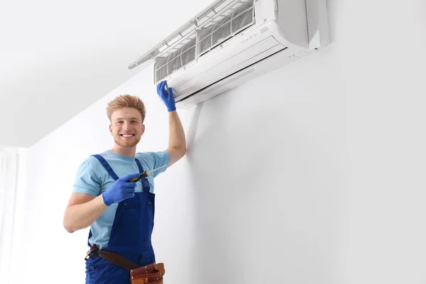 Professional technician maintaining modern air conditioner indoors — Stock Photo, Image