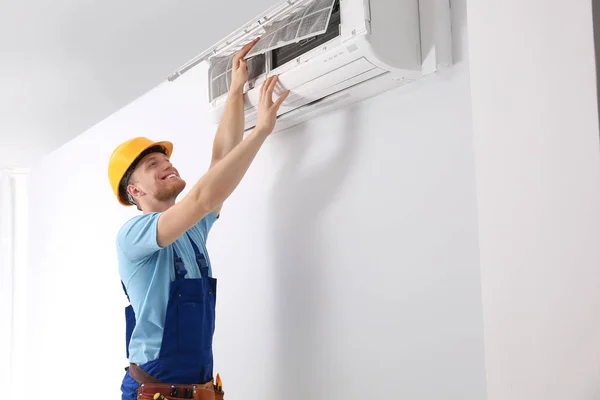 Professional technician maintaining modern air conditioner indoors — Stock Photo, Image