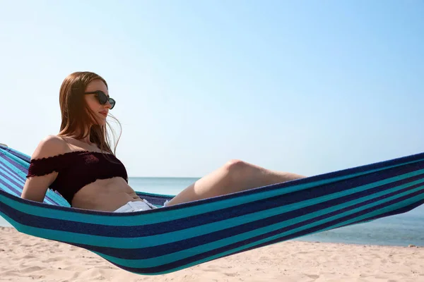 Young woman relaxing in hammock on beach — Stock Photo, Image