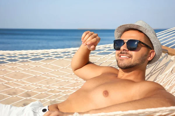 Giovane uomo rilassante in amaca sulla spiaggia — Foto Stock