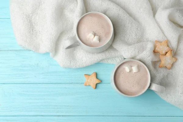 Složení s lahodným horkým kakaovým nápojem a sušenkami na světle modrém dřevěném pozadí, byt ležel — Stock fotografie