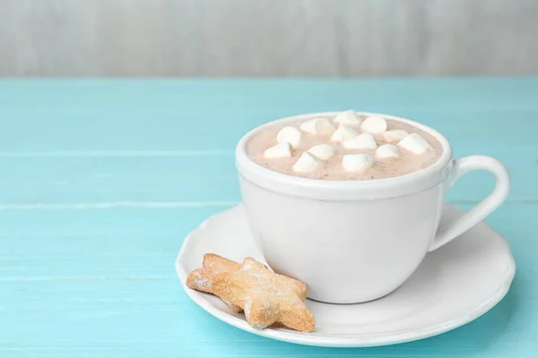 Komposition mit köstlichem Kakaogetränk in Tasse auf türkisfarbenem Holzhintergrund — Stockfoto