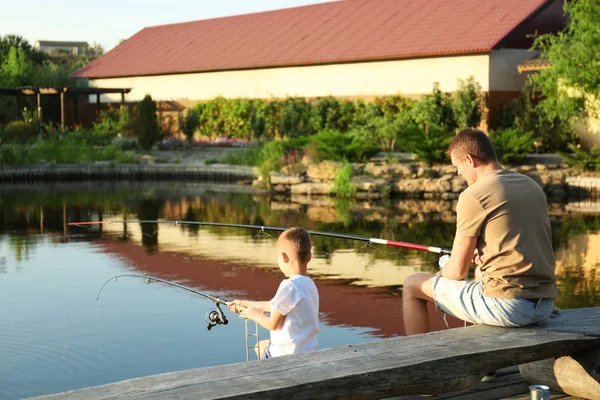 Dad and son fishing together on sunny day