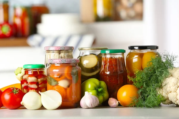 Verduras frescas y frascos de productos en escabeche sobre mesa de madera — Foto de Stock