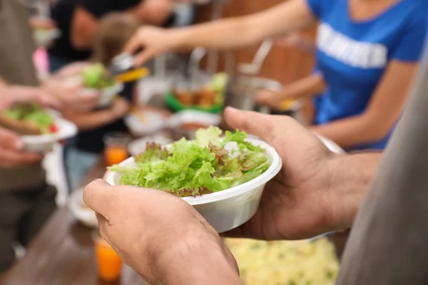 Pobre hombre sosteniendo plato con comida en el centro de caridad, primer plano — Foto de Stock