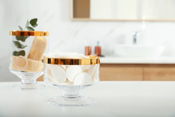 Frascos con almohadillas de algodón y esponjas de esponja en la mesa en el baño — Foto de Stock