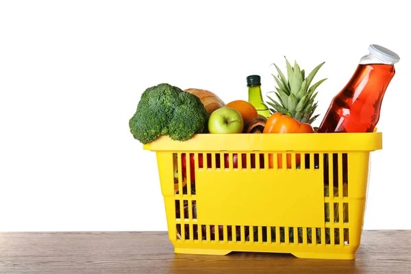 Panier avec produits d'épicerie sur table en bois sur fond blanc. Espace pour le texte — Photo