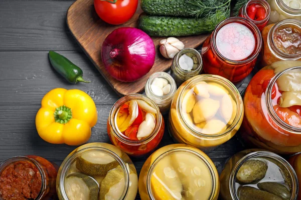 Flat lay composition with jars of pickled vegetables on grey wooden table — ストック写真