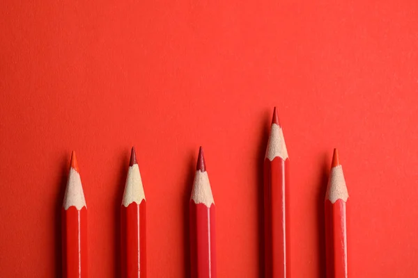 Επίπεδη σύνθεση με χρωματιστά μολύβια σε κόκκινο φόντο — Φωτογραφία Αρχείου