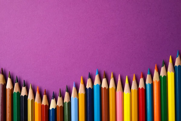 Composición plana con lápices de color sobre fondo púrpura. Espacio para texto — Foto de Stock